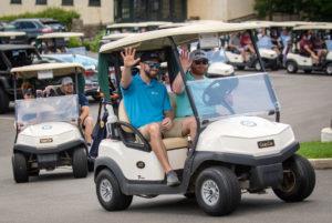 photo of men in golf cart going to golf outing